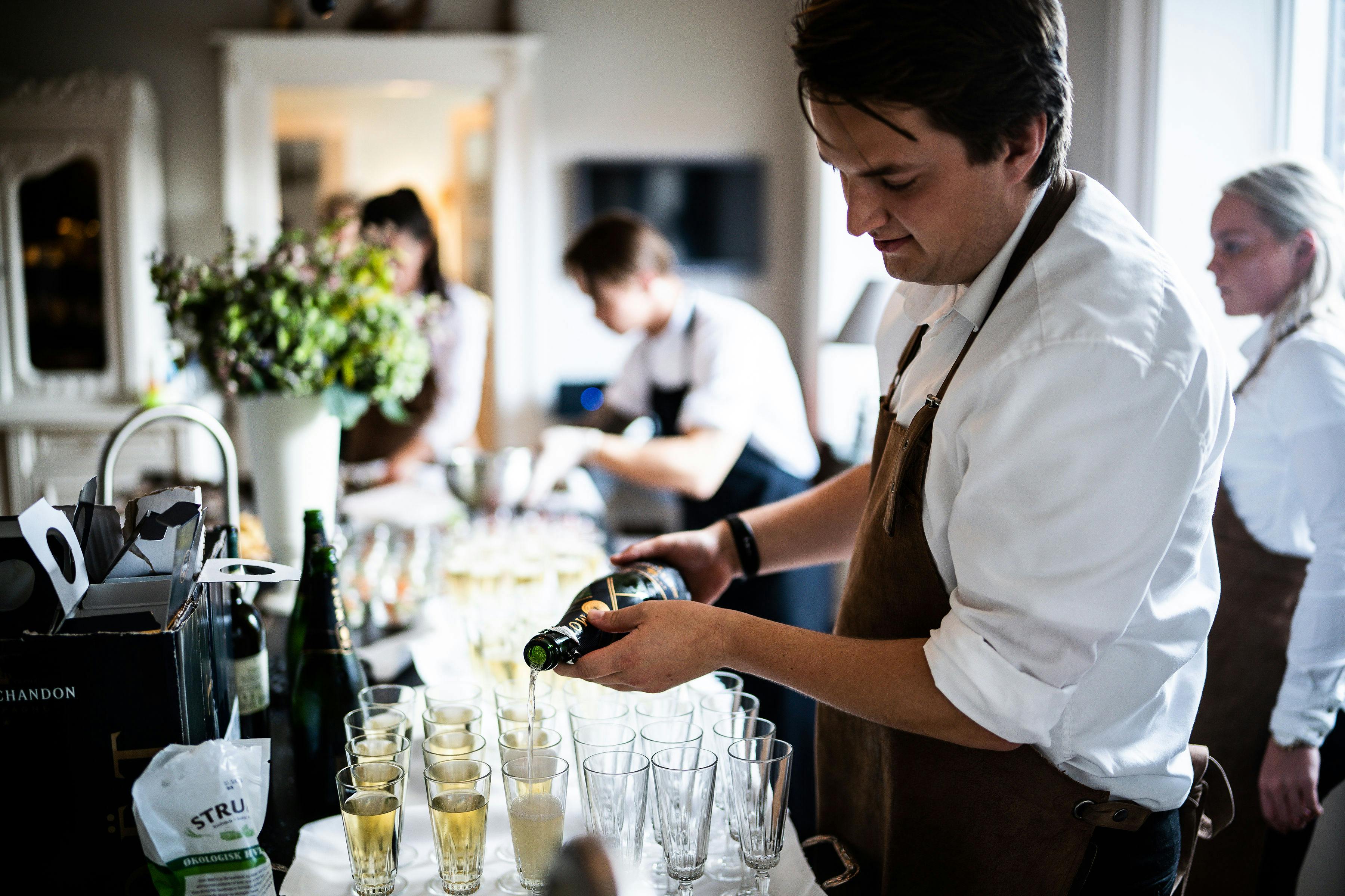 Staff member fills glasses of champagne for wedding reception